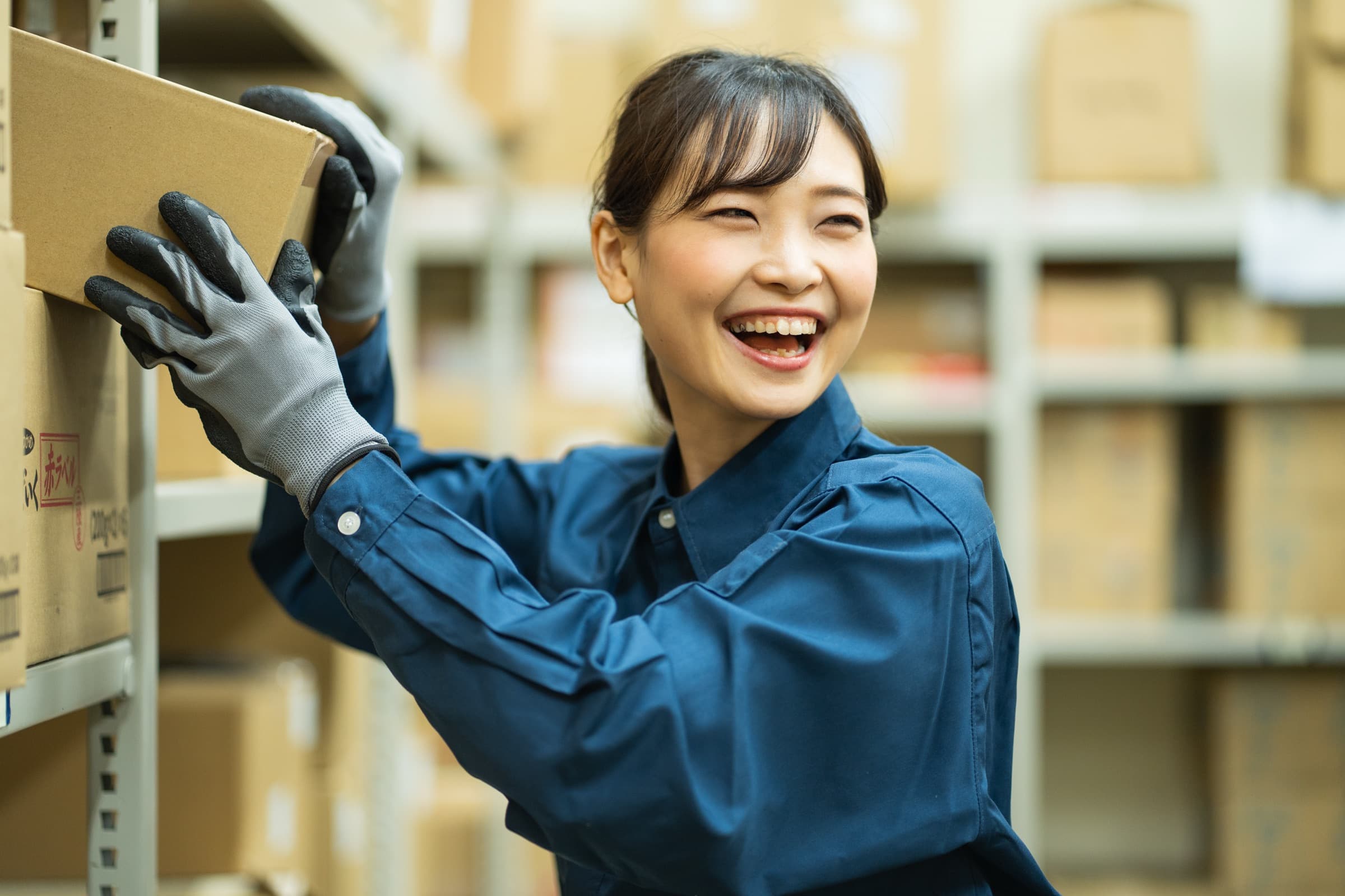 倉庫で女性が段ボールを棚に上げている